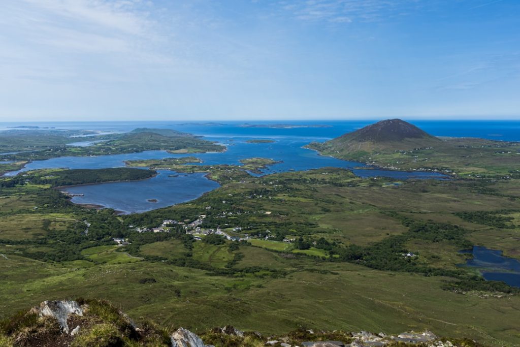 Expansive landscape featuring lakes, green hills, and distant ocean