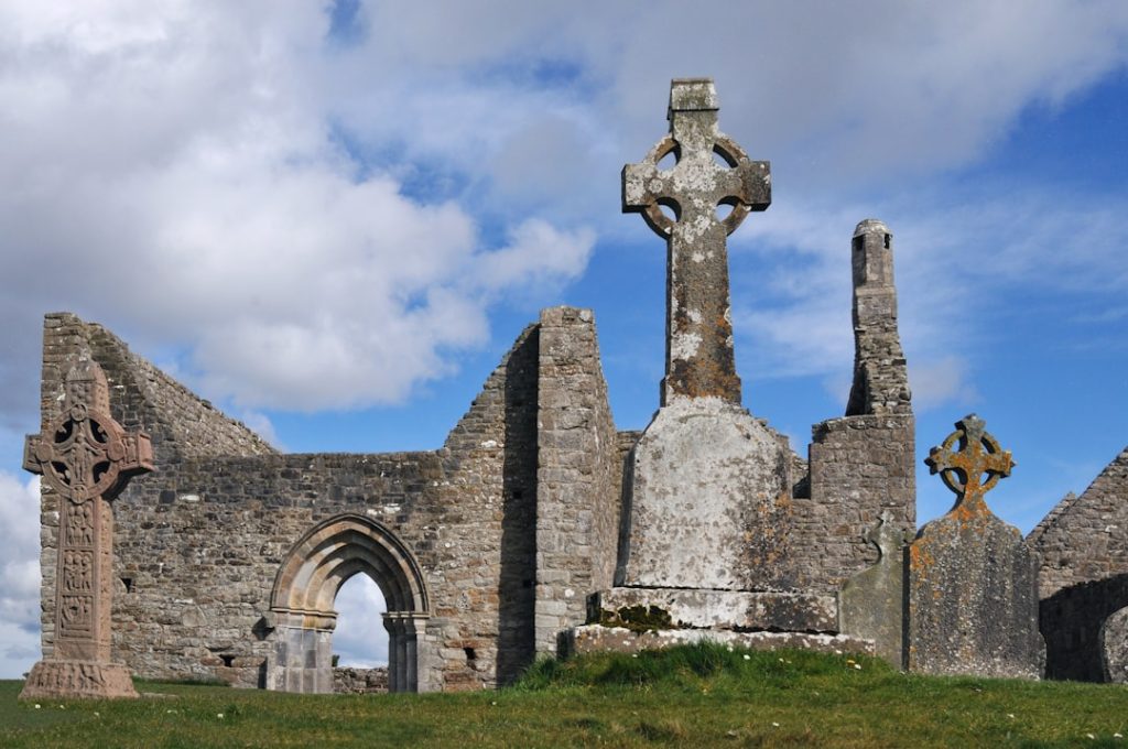 Ancient stone ruins with celtic crosses under a cloudy sky