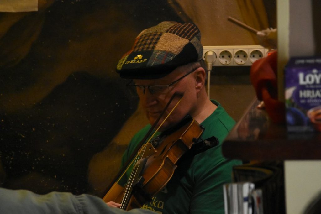 Man in a cap playing the violin indoors