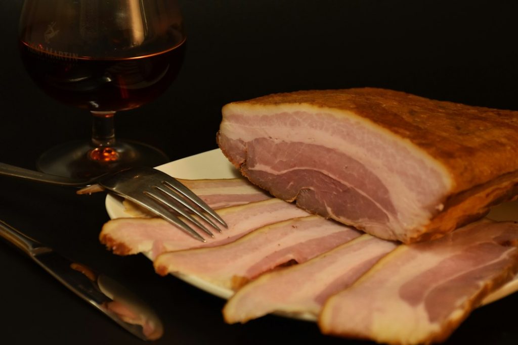 A block of smoked bacon with slices on plate