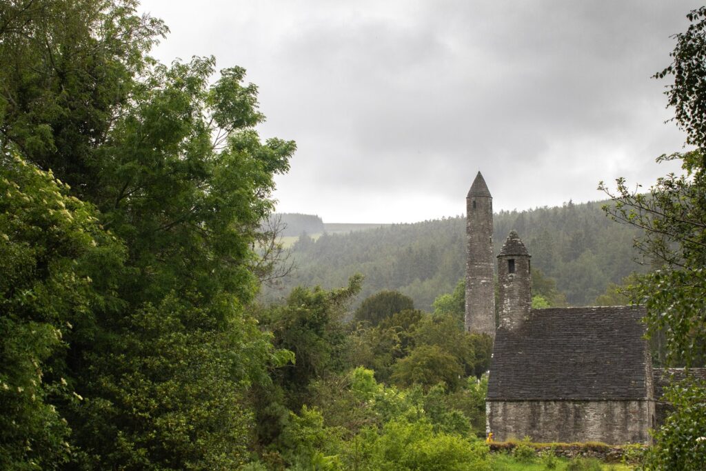 The early medieval monastic site of Glendalough on an overcast day: the slender 30-metre stone round tower with its conical