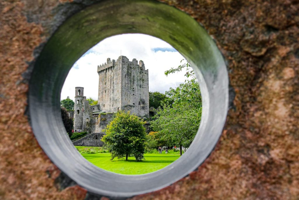 a view of a castle through a hole in a rock wall